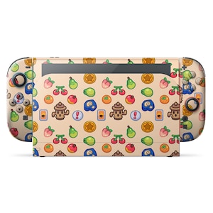 May include: A Nintendo Switch console with a custom skin featuring a repeating pattern of fruits, coins, and other game-related icons in various colours on a tan background. The controllers have matching designs.