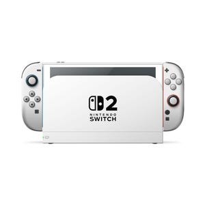 Puede incluir: Una consola de videojuegos Nintendo Switch 2 blanca con una base central que tiene el logotipo de Nintendo Switch 2 impreso en negro. El dispositivo incluye dos mandos blancos desmontables a los lados, cada uno equipado con botones grises, joysticks y una pequeña luz indicadora verde en la esquina inferior izquierda de la base.
