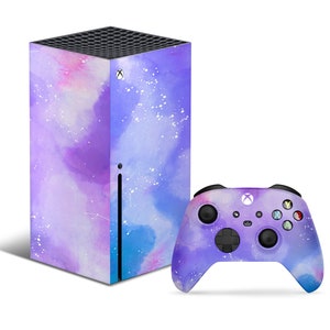 Może przedstawiać: Konsola Xbox Series X i kontroler z wzorem galaktyki w akwareli w kolorze fioletowym i niebieskim. Konsola i kontroler są pokryte wzorem galaktyki w akwareli z białymi plamkami.