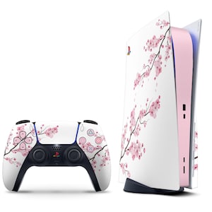 May include: A white PlayStation 5 console and controller set with a pink cherry blossom design. The console has a white exterior with a pink interior, and the controller has a matching floral pattern. The set is for gaming.