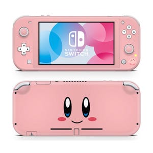 May include: A pink Nintendo Switch Lite console, featuring a screen displaying a colorful graphic and the Nintendo Switch logo. The back of the console has a cartoon character face. The console has buttons and a directional pad.