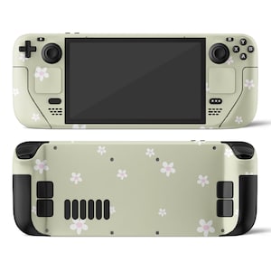 May include: A green handheld gaming console with a black screen and white flower pattern on the back. The console has a black joystick and buttons.