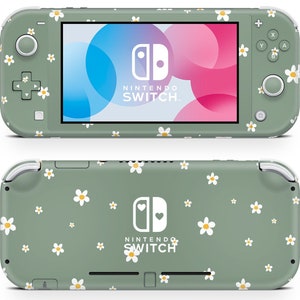 Puede incluir: Una Nintendo Switch Lite verde con un patrón de margaritas blancas. La consola tiene un logotipo de Nintendo Switch blanco con un corazón a cada lado. La pantalla muestra un degradado rosa y azul.