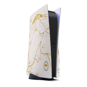 Peut inclure: Une console de jeu blanche et noire avec un motif de carte dor&eacute;. La console a une section centrale noire avec des ports et une lumi&egrave;re bleue. Le design pr&eacute;sente un motif de carte dor&eacute; sur les panneaux lat&eacute;raux blancs.