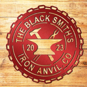 May include: Red metal sign with a chain border. The sign says "The Blacksmith's Iron Anvil Co." with a hammer and tongs crossed over an anvil. The anvil has the numbers "20" and "23" on it.