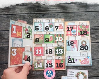 Puede incluir: Un calendario de adviento navideño de papel con cuadrados numerados del 1 al 21, con ilustraciones festivas como bastones de caramelo, regalos, muñecos de nieve y coronas. Incluye tarjetas decorativas sueltas con texto y un logotipo circular.
