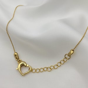 Puede incluir: Un collar de cadena de oro con un cierre en forma de coraz&oacute;n.