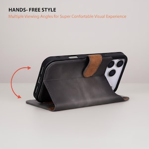 May include: A gray leather phone case with a brown clasp, propped up to display the phone's screen. The case is designed to allow multiple viewing angles. Text on the image reads "HANDS- FREE STYLE" and "Multiple Viewing Angles for Super Comfortable Visual Experience."