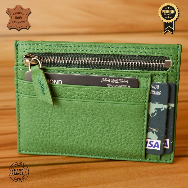 May include: Green leather card holder with a zipper closure. The card holder has two slots for cards and a zippered pocket. The card holder is made of genuine leather and is hand-made.