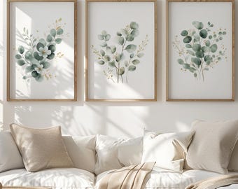 Peut inclure: Trois impressions encadrées de plantes botaniques avec des feuilles d'eucalyptus à l'aquarelle vertes et dorées. Les impressions sont affichées au-dessus d'un canapé sectionnel blanc avec des coussins beiges et une table basse ronde.