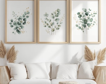 Peut inclure: Trois impressions d'art botanique encadrées avec des feuilles d'eucalyptus à l'aquarelle en vert et or. Les impressions sont dans des cadres en bois clair et sont accrochées au-dessus d'un canapé blanc.