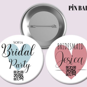 May include: Two round pin badges with a white background and a heart design. The first badge says "Sofia Bridal Party" with a light blue heart. The second badge says "Bridesmaid Jessica" with a pink heart. Both badges have a QR code.