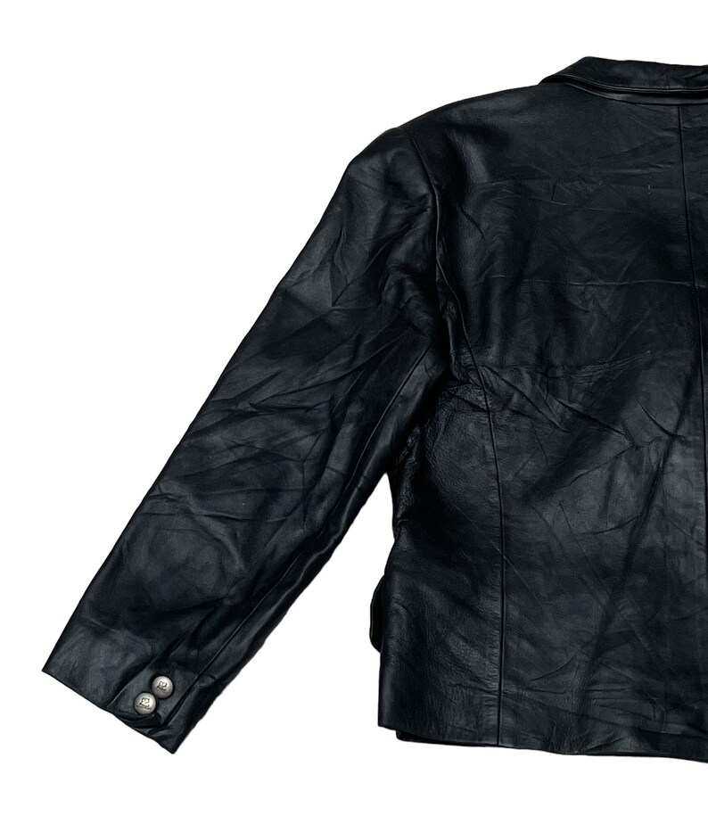 May include: A black leather jacket with a long sleeve and a button on the cuff.
