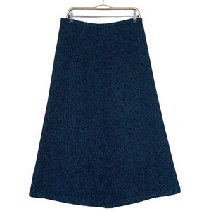 Puede incluir: Una falda azul oscuro con un patrón texturizado. La falda está colgada en una percha.