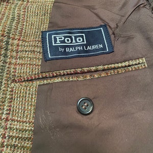 K&ouml;nnte beinhalten: Ein brauner Tweedblazer mit einem schwarzen Etikett mit der Aufschrift "Polo by Ralph Lauren".