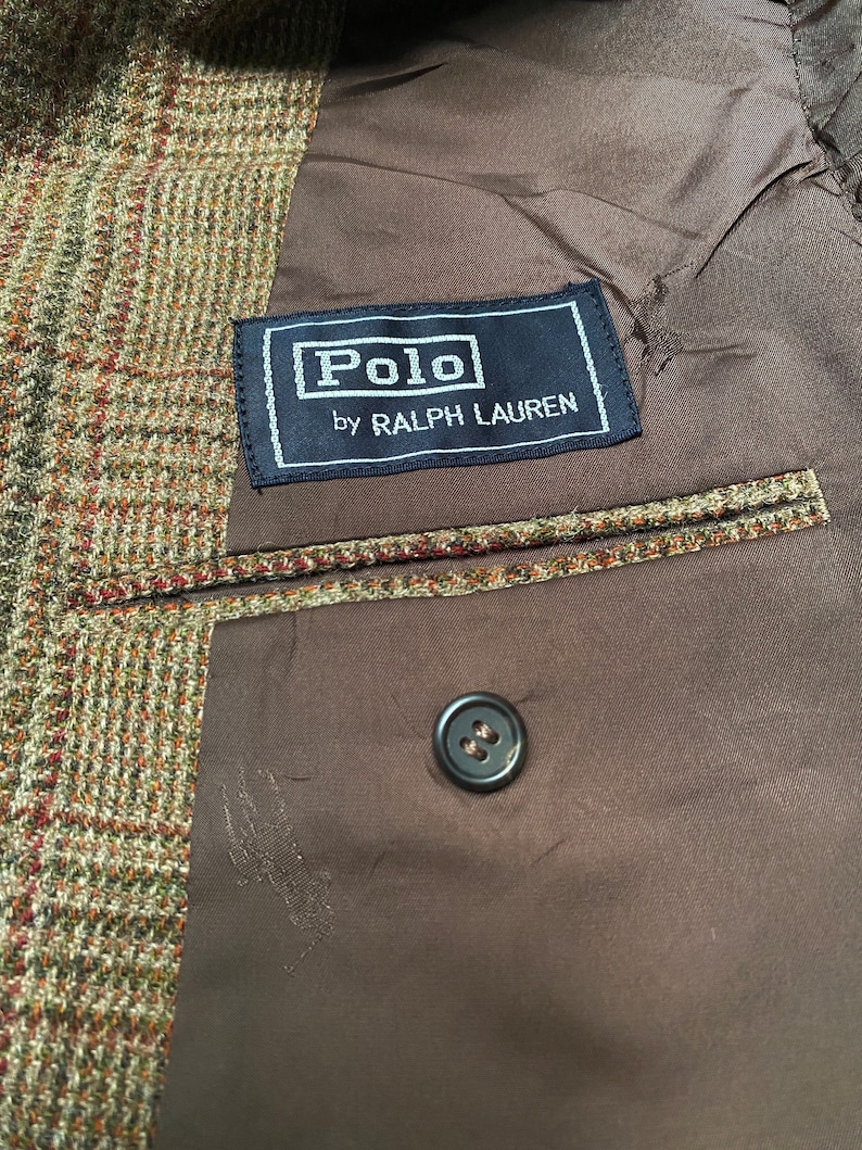 K&ouml;nnte beinhalten: Ein brauner Tweedblazer mit einem schwarzen Etikett mit der Aufschrift "Polo by Ralph Lauren".