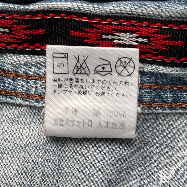May include: A white care label with washing instructions and a size 40. The label also includes a text that says "染料が色落ちしますので他の物と 一緒に洗わないでください。 タンブラー乾燥は、お避けくたさい。 本体編 100% 前ポケットロ 人工皮革".