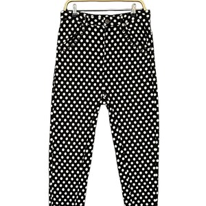 May include: Black and white polka dot pants hanging on a hanger. The pants are a slim fit and have a high waist.