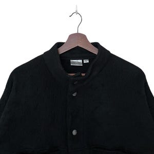 May include: A black fleece jacket with a snap button closure and a stand-up collar.