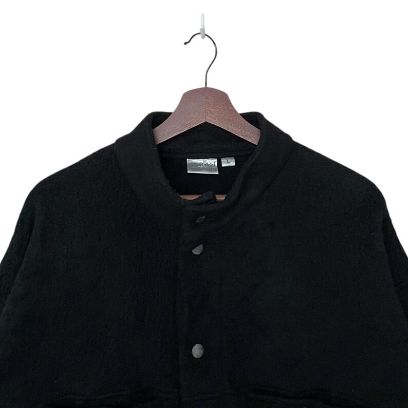 May include: A black fleece jacket with a snap button closure and a stand-up collar.