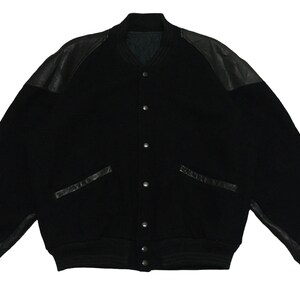 May include: A black varsity jacket with leather sleeves and pockets. The jacket has a button closure and a ribbed collar, cuffs, and hem.