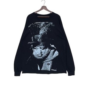 May include: Black long-sleeve t-shirt with a white graphic print of a man wearing a hat and scarf. The graphic is of a man with a mustache and beard, and the text "The Shorty Manhole" is printed below the graphic.