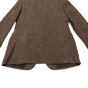 K&ouml;nnte beinhalten: Ein brauner Tweedblazer mit Karomuster. Der Blazer hat einen einreihigen Verschluss und einen Schalkragen.