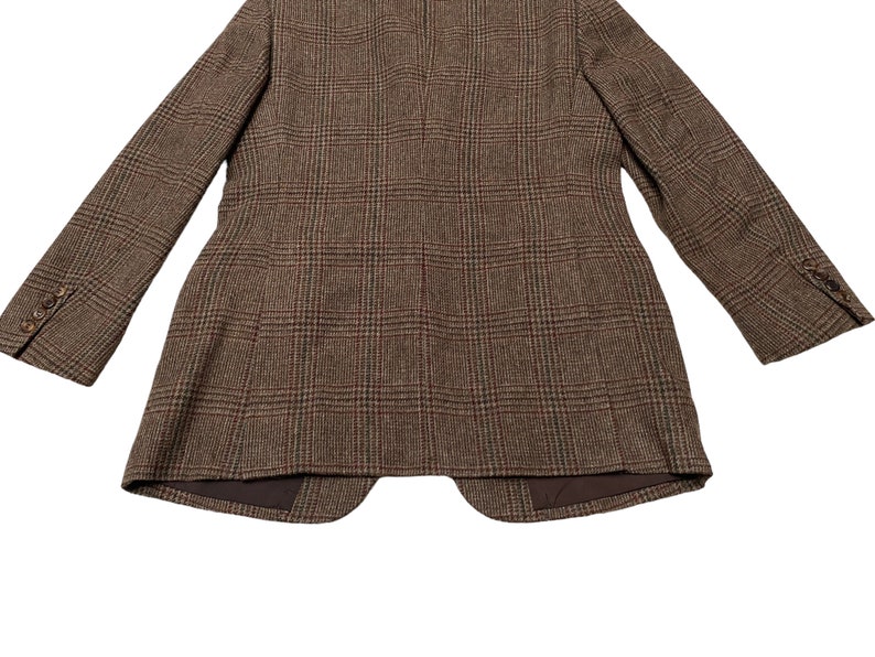 K&ouml;nnte beinhalten: Ein brauner Tweedblazer mit Karomuster. Der Blazer hat einen einreihigen Verschluss und einen Schalkragen.