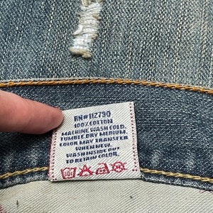 May include: A white care label with black text that reads "RN#112790 100% COTTON MACHINE WASH COLD TUMBLE DRY MEDIUM COLOR MAY TRANSFER WHEN NEW. WASH INSIDE OUT TO RETAIN COLOR."