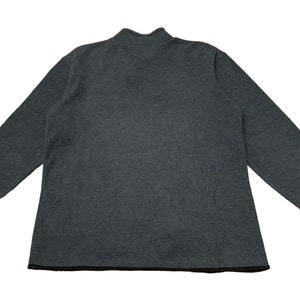 May include: A dark gray long-sleeved sweater with a mock neck and black trim around the neckline and sleeves.