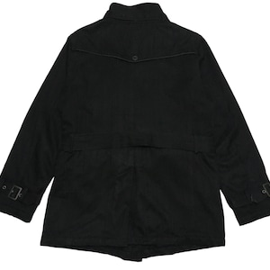 Puede incluir: Una chaqueta negra de manga larga con cuello alto, cinturón y dos bolsillos en la parte delantera.