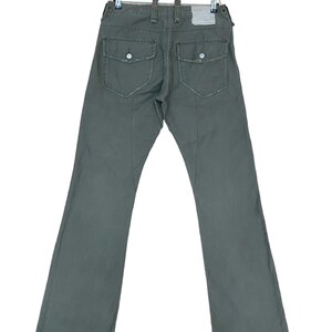 May include: A pair of dark green cargo trousers with large pockets on the back. The trousers have a straight leg and a relaxed fit.