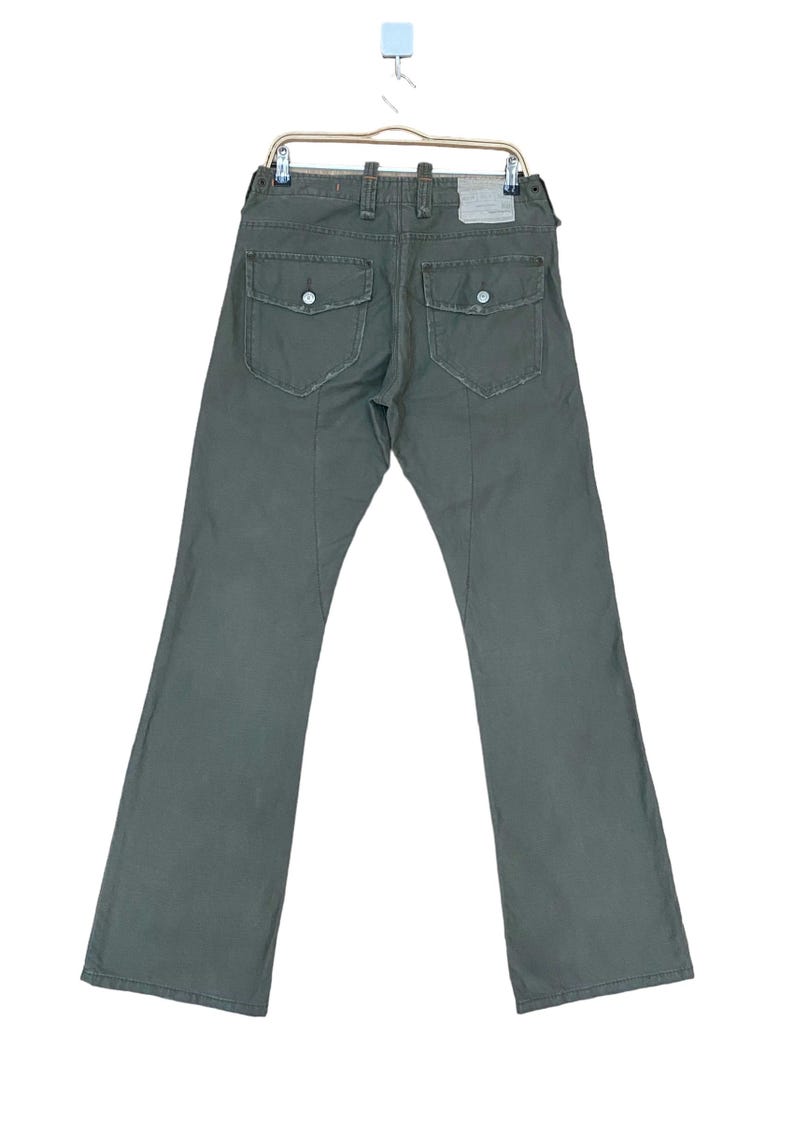May include: A pair of dark green cargo trousers with large pockets on the back. The trousers have a straight leg and a relaxed fit.