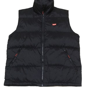 Può includere: Un giubbotto imbottito nero con chiusura a zip e due tasche con zip. Il giubbotto ha un logo "Levi's" rosso sul davanti.