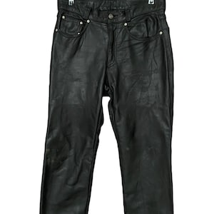 May include: Black leather pants hanging on a hanger. The pants have a classic five-pocket design and a straight leg.