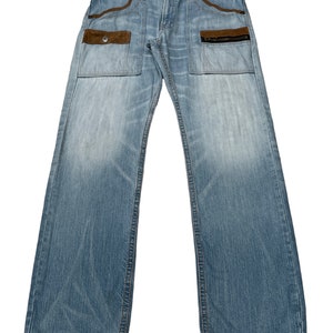 May include: Light blue denim jeans with brown suede patch pockets and zippered details.