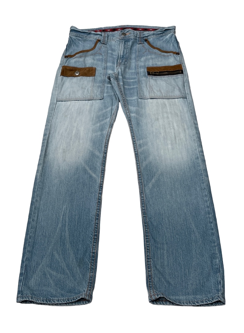 May include: Light blue denim jeans with brown suede patch pockets and zippered details.