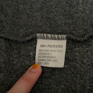 May include: A white care label with black text that reads "100% Polyester, Machine Wash Cold Separately, Do Not Bleach, Tumble Dry Low, Cool Iron."