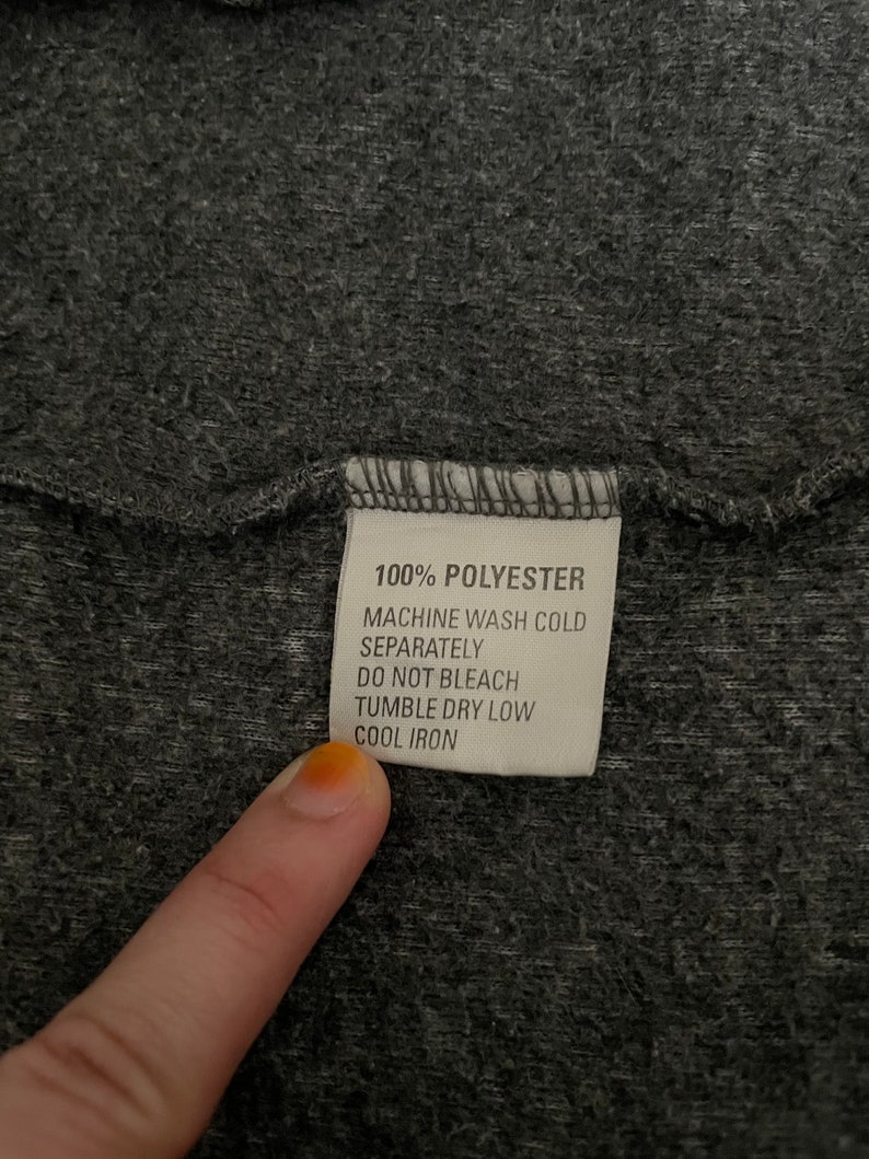 May include: A white care label with black text that reads "100% Polyester, Machine Wash Cold Separately, Do Not Bleach, Tumble Dry Low, Cool Iron."