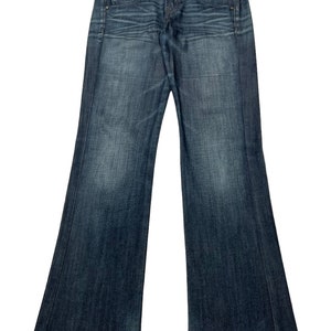 May include: A pair of dark blue denim jeans with a bootcut leg style. The jeans have a button fly and belt loops.