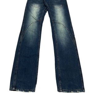 Peut inclure: Un jean bleu denim avec plusieurs poches et des détails de fermeture éclair. Le jean a un aspect délavé et est délavé aux ourlets.