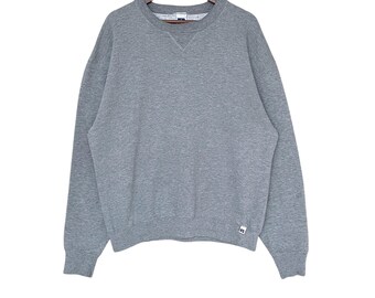 May include: A gray long-sleeved sweatshirt with a crew neck and a small logo on the bottom right.