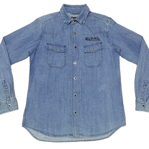 May include: A light blue denim long-sleeve shirt with a button-down collar and a black embroidered logo that says "Van Dutch".