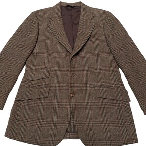 K&ouml;nnte beinhalten: Ein brauner Blazer mit Karomuster und einem Knopfverschluss. Der Blazer hat zwei Pattentaschen auf der Vorderseite und ein braunes Futter.