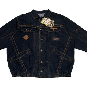 Puede incluir: Una chaqueta vaquera azul oscuro con costuras marrones y múltiples bolsillos. La chaqueta tiene cierre de botones y una etiqueta con el texto "Blue Ice" en la parte delantera.