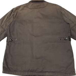 Puede incluir: Una chaqueta de trabajo marr&oacute;n con cierre de botones y dos bolsillos de solapa en la espalda.