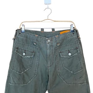 May include: Green cargo trousers with large pockets and distressed details.