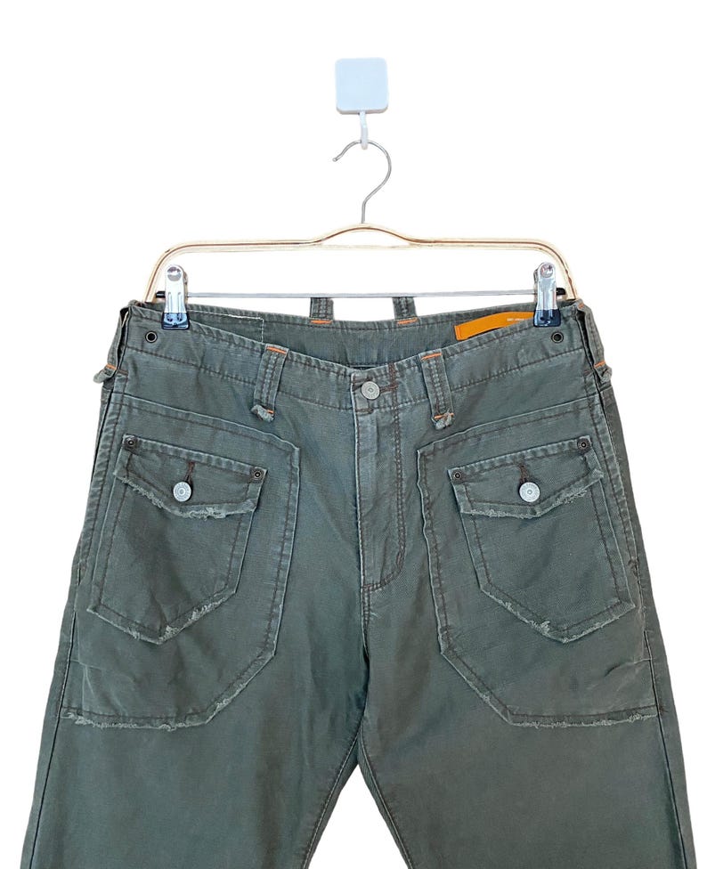 May include: Green cargo trousers with large pockets and distressed details.