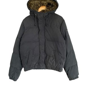 May include: A black puffer jacket with a hood lined with brown faux fur. The jacket has a zip closure, two front pockets, and a drawstring hood. The jacket is a size medium.