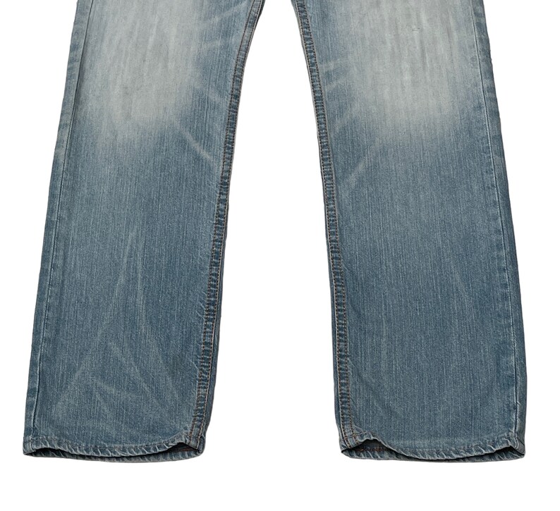 May include: A pair of light blue denim jeans with a straight leg fit. The jeans have a classic five-pocket design and are made from a soft, comfortable cotton blend.